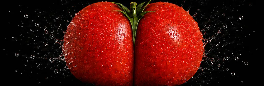 A tomato, split down the middle, caught in a burst of water